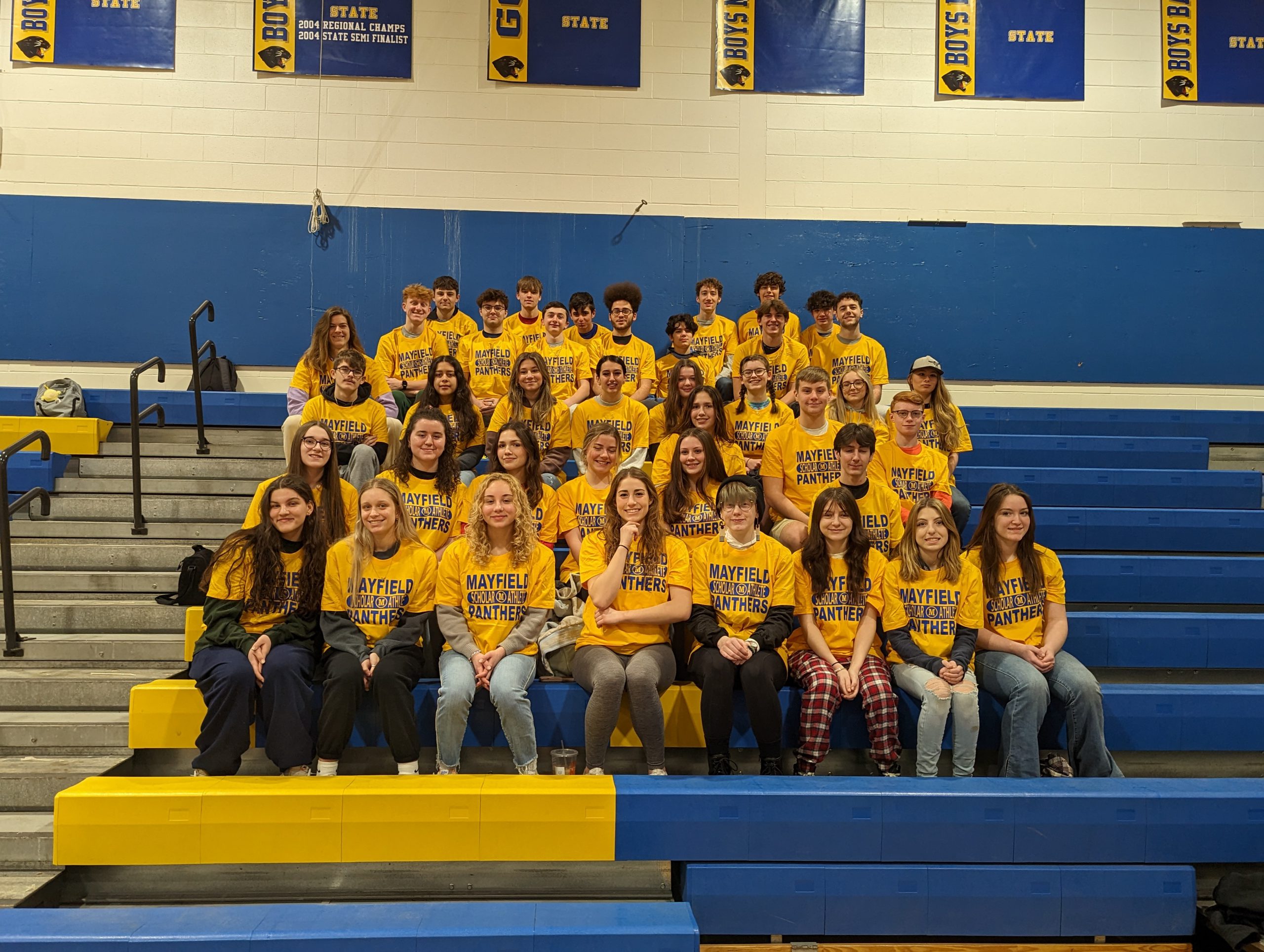 Group of Scholar-Athletes wearing matching t-shirts seated on bleachers
