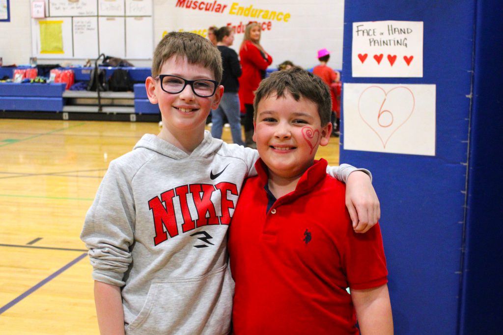 Two students stand together in a gym