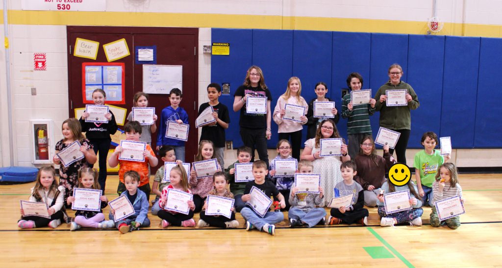 students sit in three rows and hold certificates
