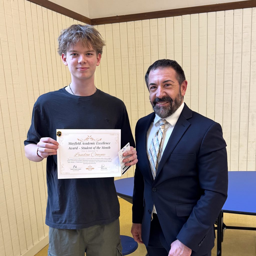 student holds a certificate and stands with administrator in a suit