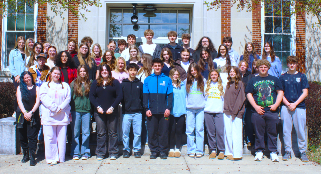 group of students stand outside in front of school doors