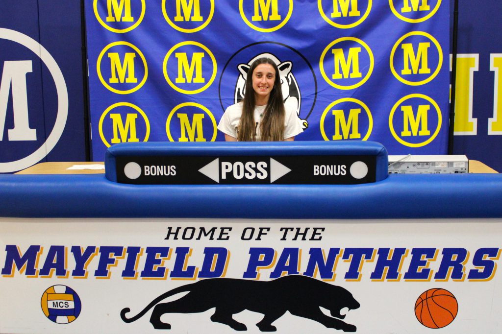 students sitting in front of a score keeper and sign that says Home of the Panthers