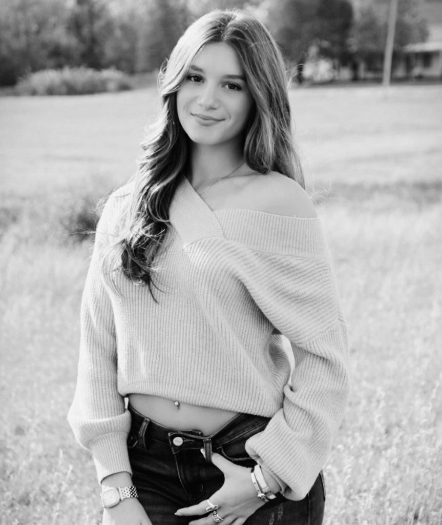 student in sweater standing in a field
