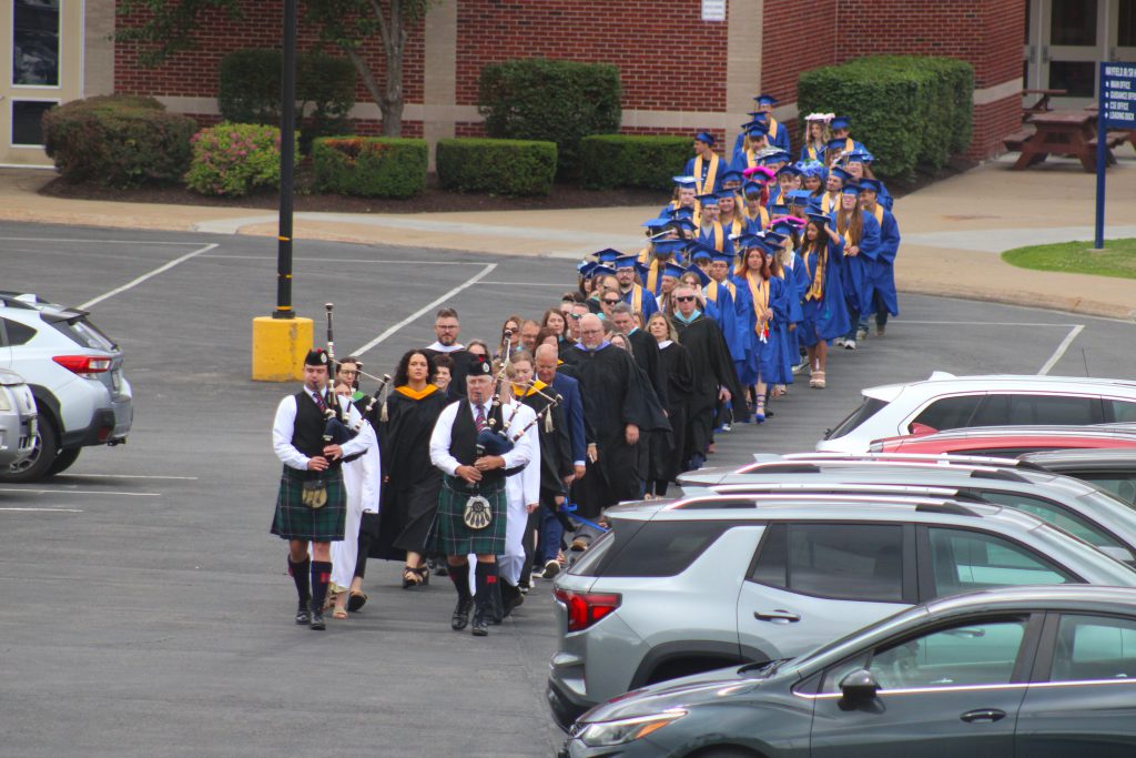 Bagpipers lead teachers and graduates through parking lot