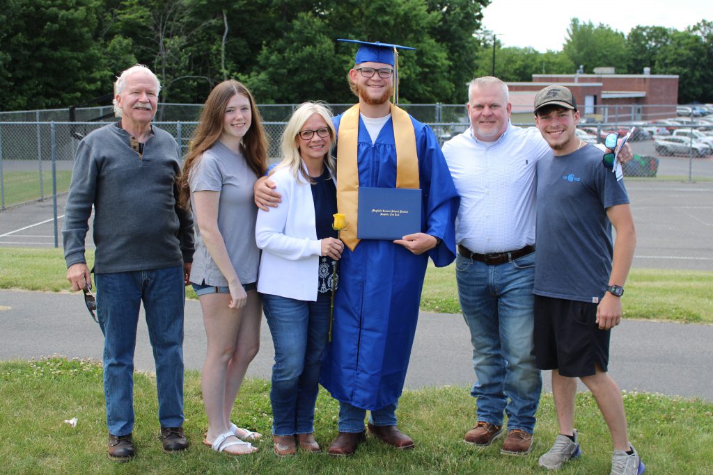 Family stands with graduate in cap and gown