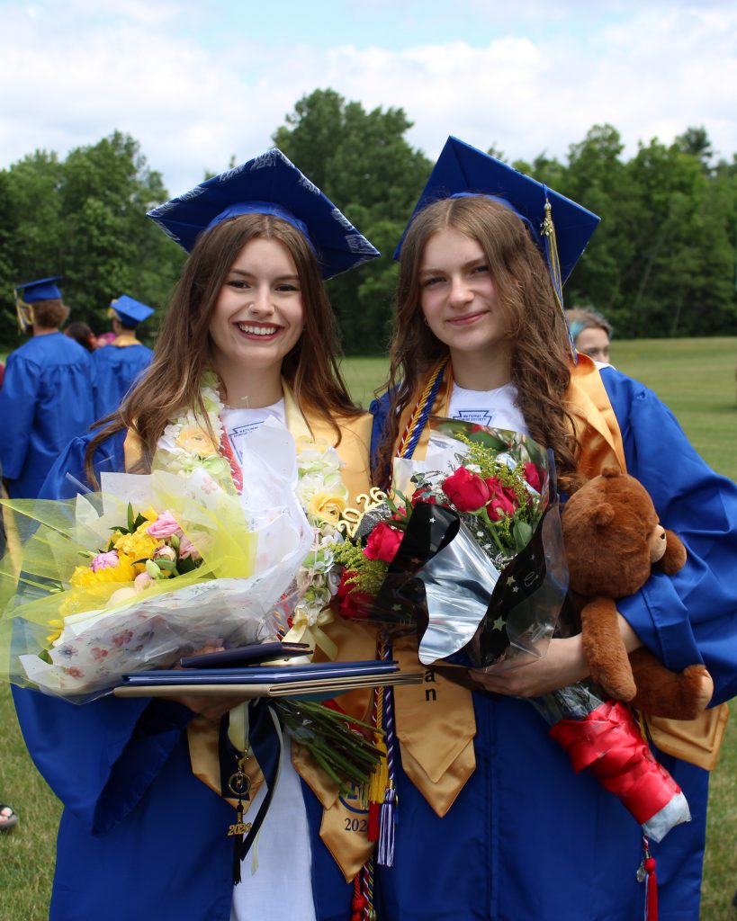 Two graduates hold flowers