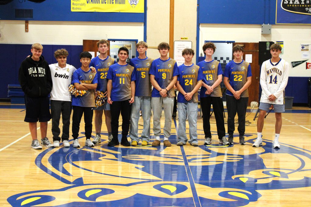 Student athletes wearing uniforms stand in a line in the gym