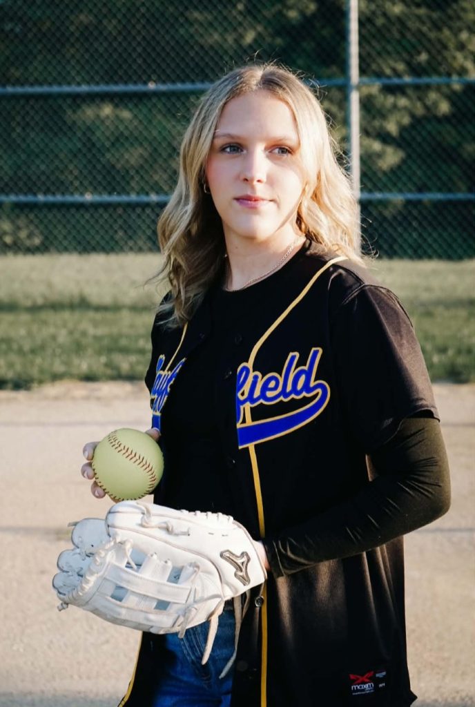 Student in Mayfield uniform holding a softball and glove
