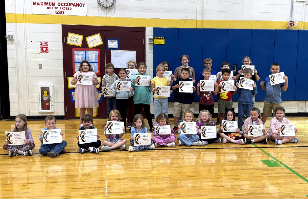 Students stand in three rows holding certificates
