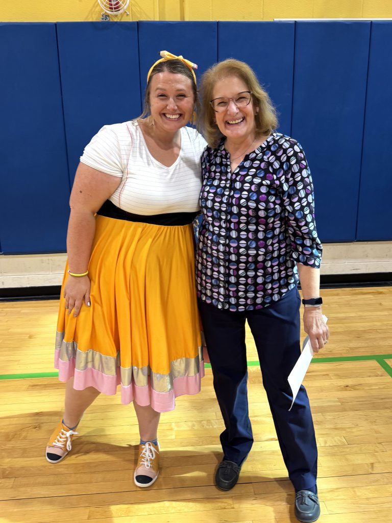 Two teachers stand together and smile