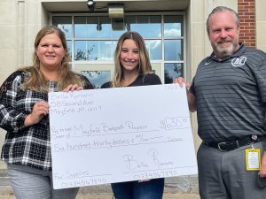 three people standing with check donation