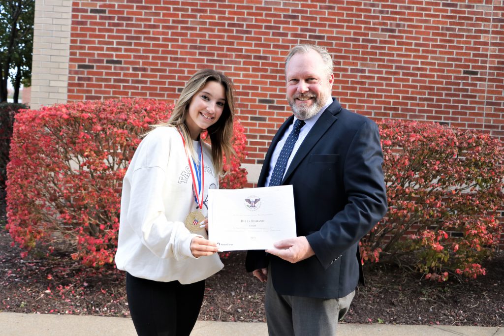 Principal and student posing with award