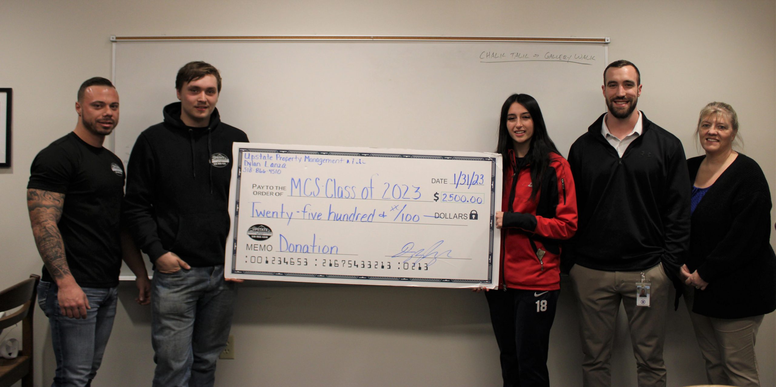 five people stand with a large check for $2500