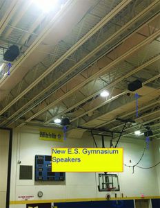 Speakers attached to the ceiling of the gymnasium