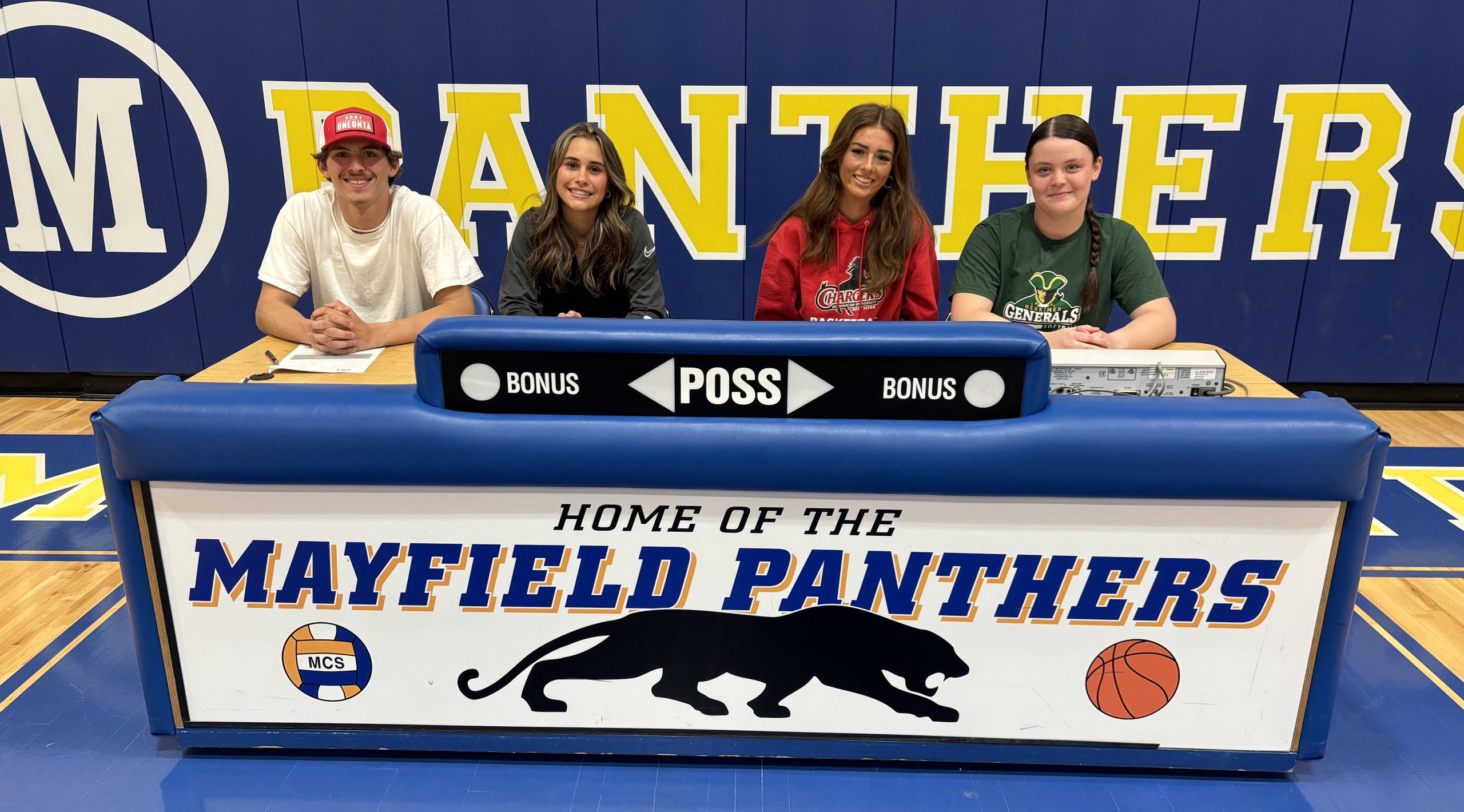 four student athletes sit behind a podium reading "Mayfield Panthers"