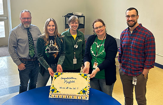 5 people standing behind a cake that says Congratulations Mayfield. We are off the list!!