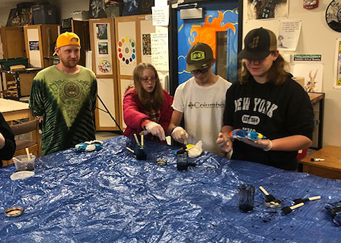 Kyle (in yellow hat) and 3 students at a table