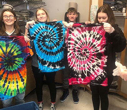 4 students holding tie dyed shirts