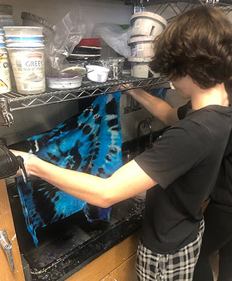 student holding shirt over sink