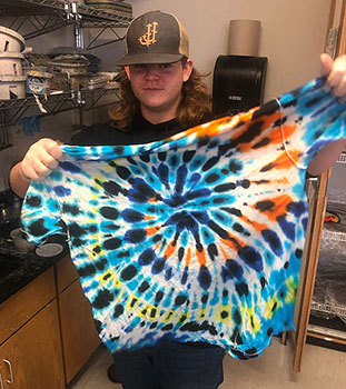 student holding finished tie dyed shirt