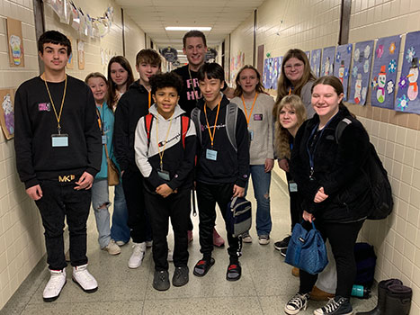 A group of HS students with Pat Fish in a hallway
