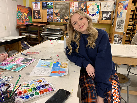 Maya sitting at a table in the art classroom