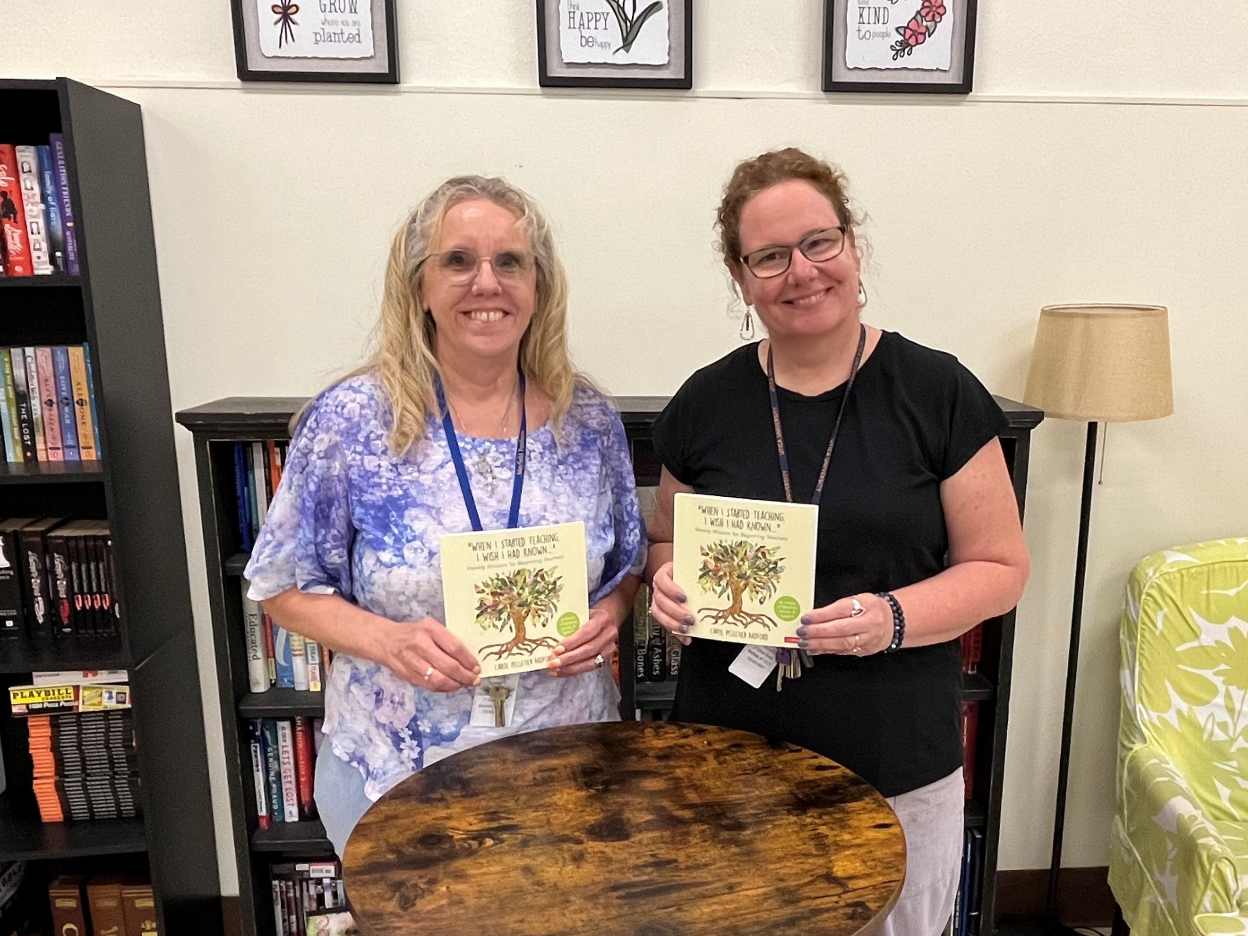 two people stand in front of a table holding books