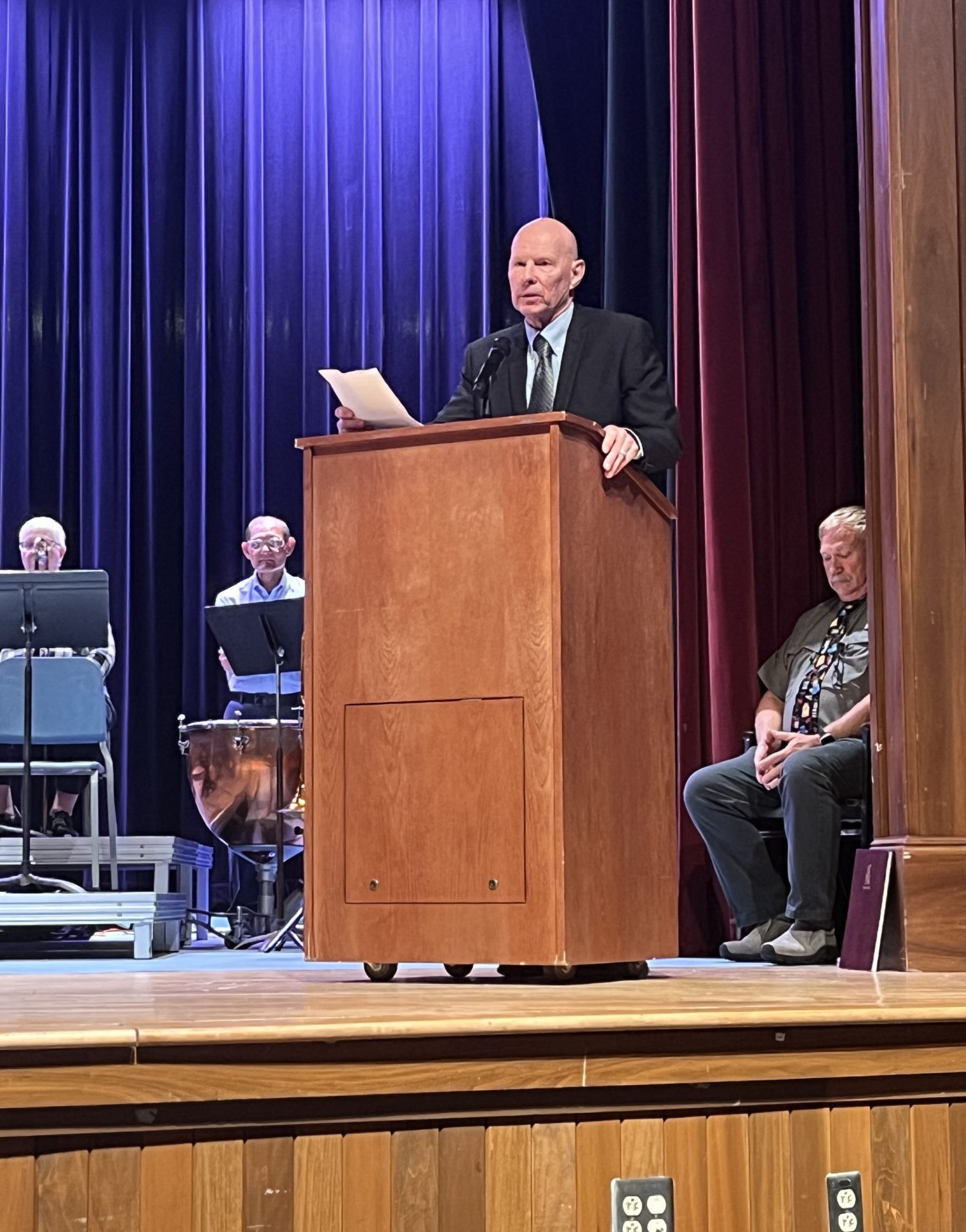 man in a suit stands at the podium