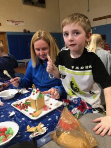 Student works with his mom on a Gingerbread house