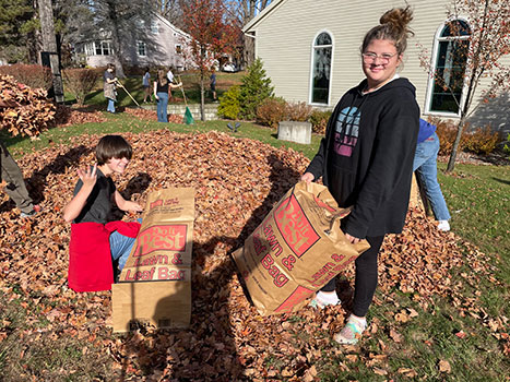 2 students raking and bagging leaves