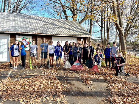 group of students standing with rakes in leaves