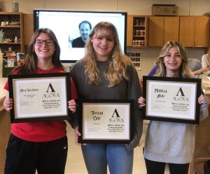 three students hold up their awards