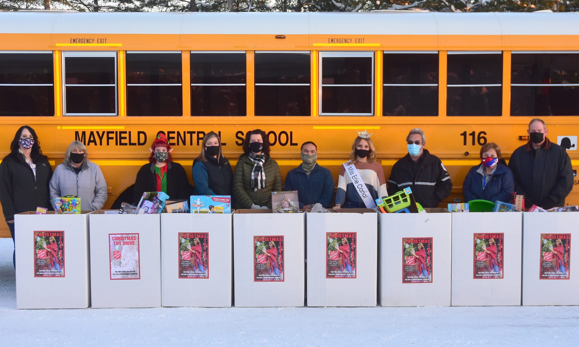 Transportation staff lined up with toys in front of a Mayfield bus