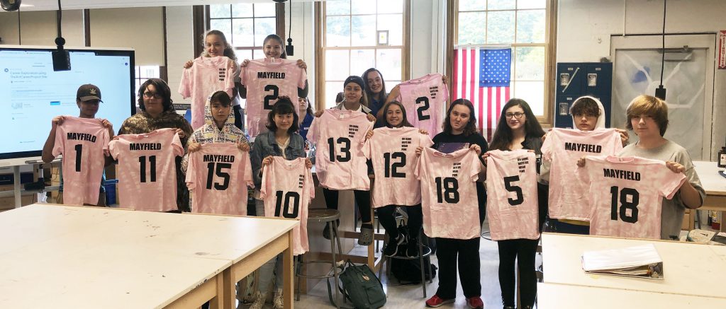 Students holding tee shirts in class