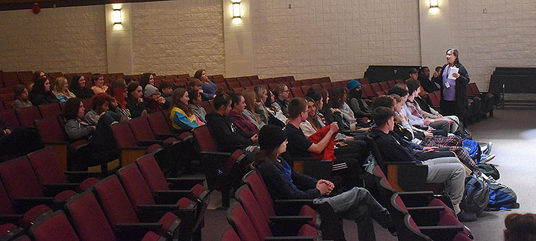 adult talking to large group of students sitting in the auditorium