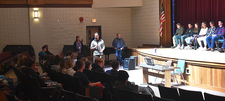 adult talking to large group of students sitting in the auditorium