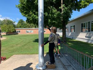 student turning handle on flag pole