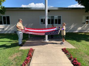 Scout leader and student folding the flag