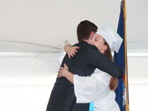 Principal hugs student before giving diploma