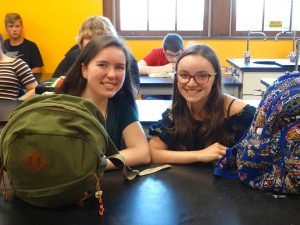 Students hold book bags in class