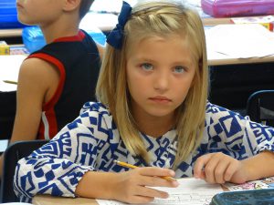 Student in blue top writing in class