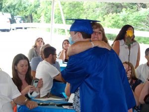 Student hands out flower to a loved one