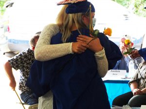 Student hugs parent after giving her a flower