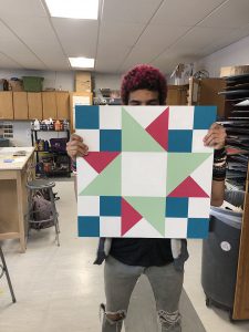 Student holding square in front of him