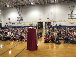 Principal dressed as a queen addresses the assembly