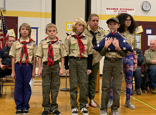 Scouts standing, holding folded flag